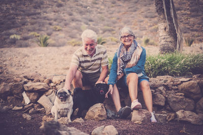 Senior couple with dogs sitting on rocks