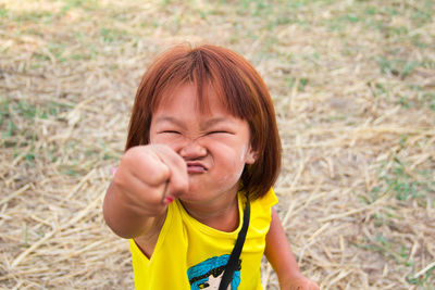 High angle view girl with eyes closed clenching fist while standing on land