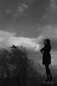 Rear view of woman standing on field against sky