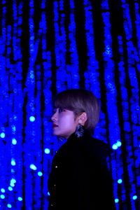 Side view portrait of girl standing against blue sky