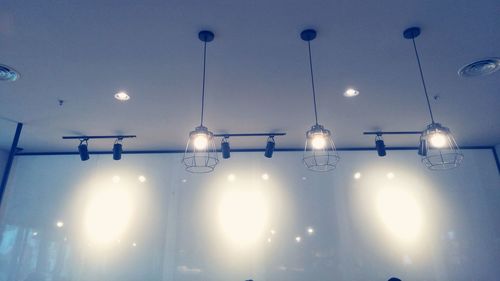 Low angle view of illuminated pendant lights hanging from ceiling