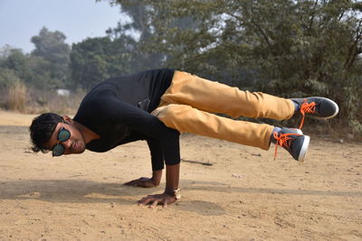 Portrait of man wearing sunglasses performing handstand outdoors