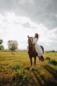 Young woman riding horse on field