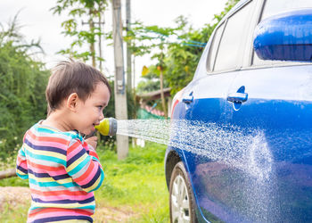 Cute boy washing car outdoors