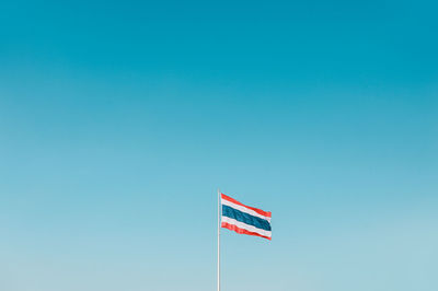 Low angle view of thai flag against clear blue sky