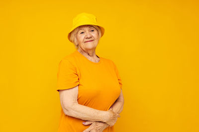 Portrait of young woman standing against yellow background