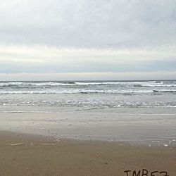 Scenic view of beach against cloudy sky