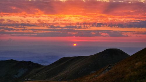 Scenic view of mountain against dramatic sky during sunset