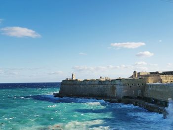 Buildings by sea against blue sky