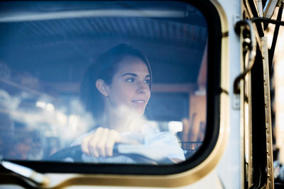 Young saleswoman looking away while driving food truck