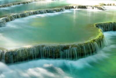 Scenic view on a cascaded kuang si waterfall with turquoise water on a sunny laos.