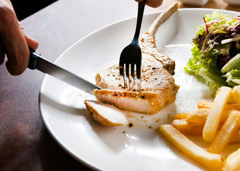 Cropped hand of person having food in plate