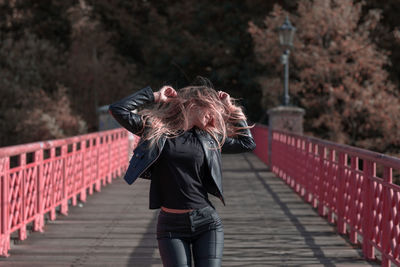 Young woman with blond hair standing on footbridge