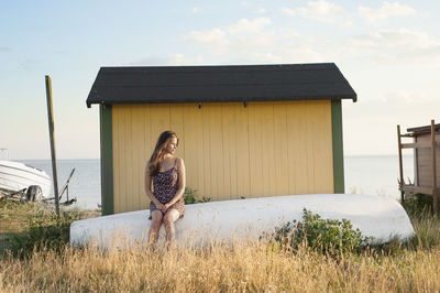 Young woman sitting behind beach hut