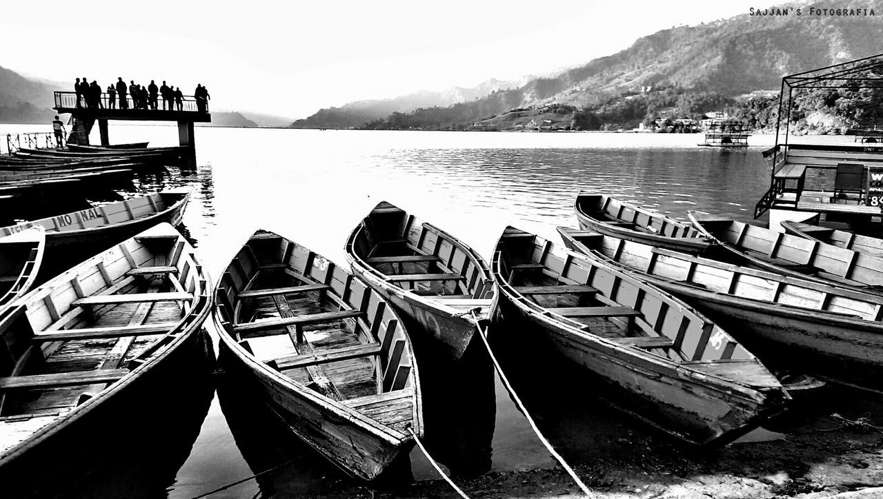 mountain, water, nautical vessel, built structure, moored, mountain range, boat, architecture, sea, building exterior, transportation, nature, sky, tranquility, lake, mode of transport, pier, railing, tranquil scene, scenics