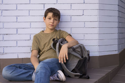 Portrait of boy sitting against wall
