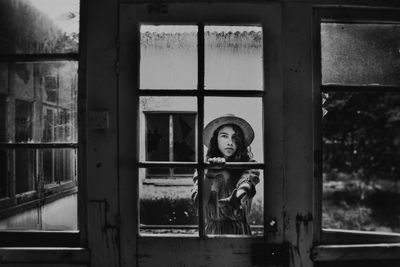 Girl reaching out through broken window