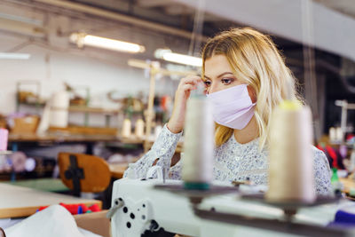 Woman wearing mask while working in factory