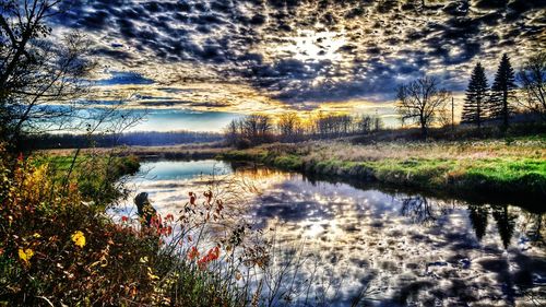 Scenic view of calm lake against cloudy sky during sunset