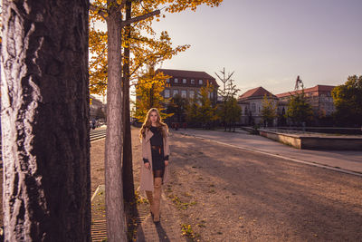 Woman walking by trees in city during autumn