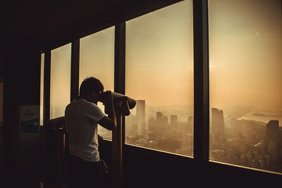 Rear view of man photographing through window