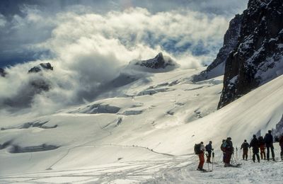 Hikers on snow covered landscape against sky