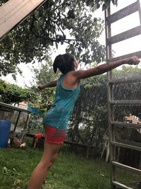 Full length of young woman standing by tree against sky