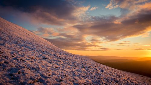 Scenic view of snow covered landscape against sky during sunset