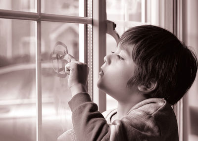Close up of boy touching window at home