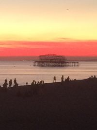 Silhouette people on beach against sky during sunset