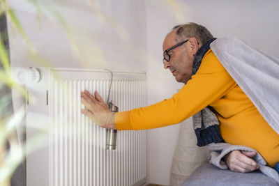 Senior man checking radiator temperature at home