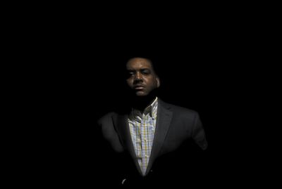 Portrait of young man standing against black background