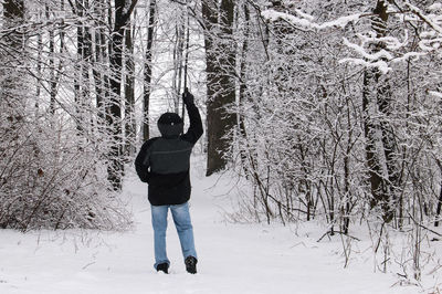 Rear view of woman standing on snow covered tree