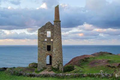 Built structure on beach by sea against sky