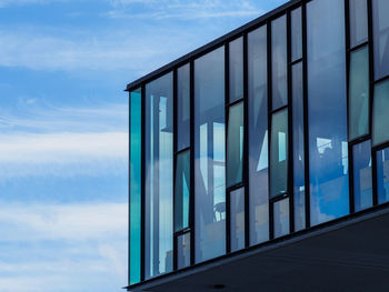 Low angle view of modern glass building against sky