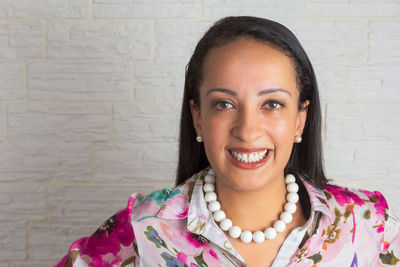 Portrait of smiling young woman against wall