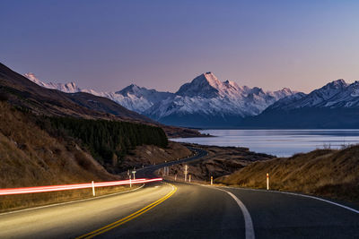 Light trails on road by mountains against clear sky at aoraki mount cook national park, new zealand