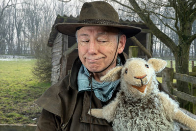 Smiling man with puppet against trees