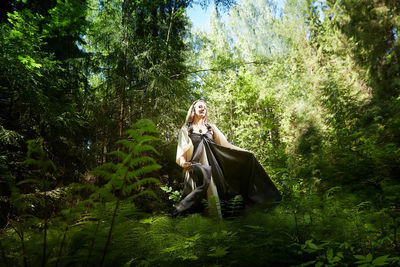 Rear view of woman standing in forest
