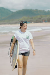 Portrait of young woman standing at beach