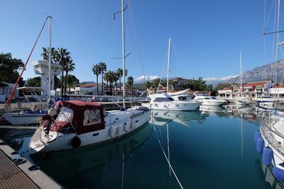 Sailboats moored at harbor against blue sky