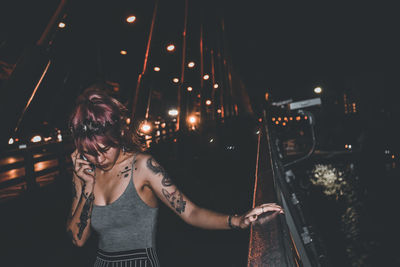 Woman standing by illuminated lights at night