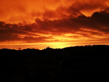 Silhouette landscape against dramatic sky during sunset