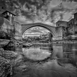 Arch bridge over river against sky