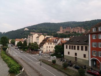 Road by buildings in city against sky