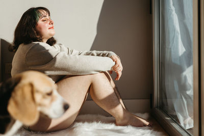 Side view of young woman using laptop at home
