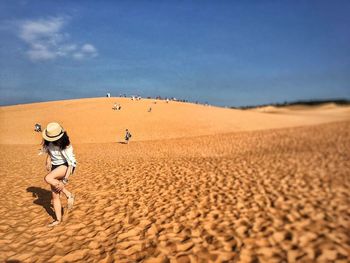 Man standing on sand dune in desert against clear sky