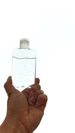 Close-up of hand holding bottle against white background