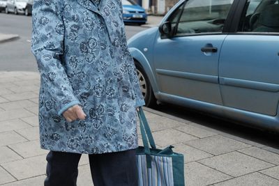 Midsection of woman standing by car