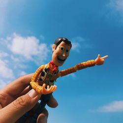 Low angle view of woman holding toy against sky